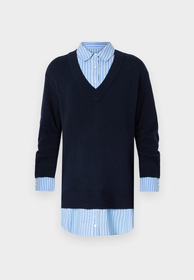 Navy V-Ausschnitt Pulli, der über einem hellblau gestreiften Hemd getragen wird, mit langen Ärmeln und knöpfbaren Manschetten sowie einem gerippten Saum.