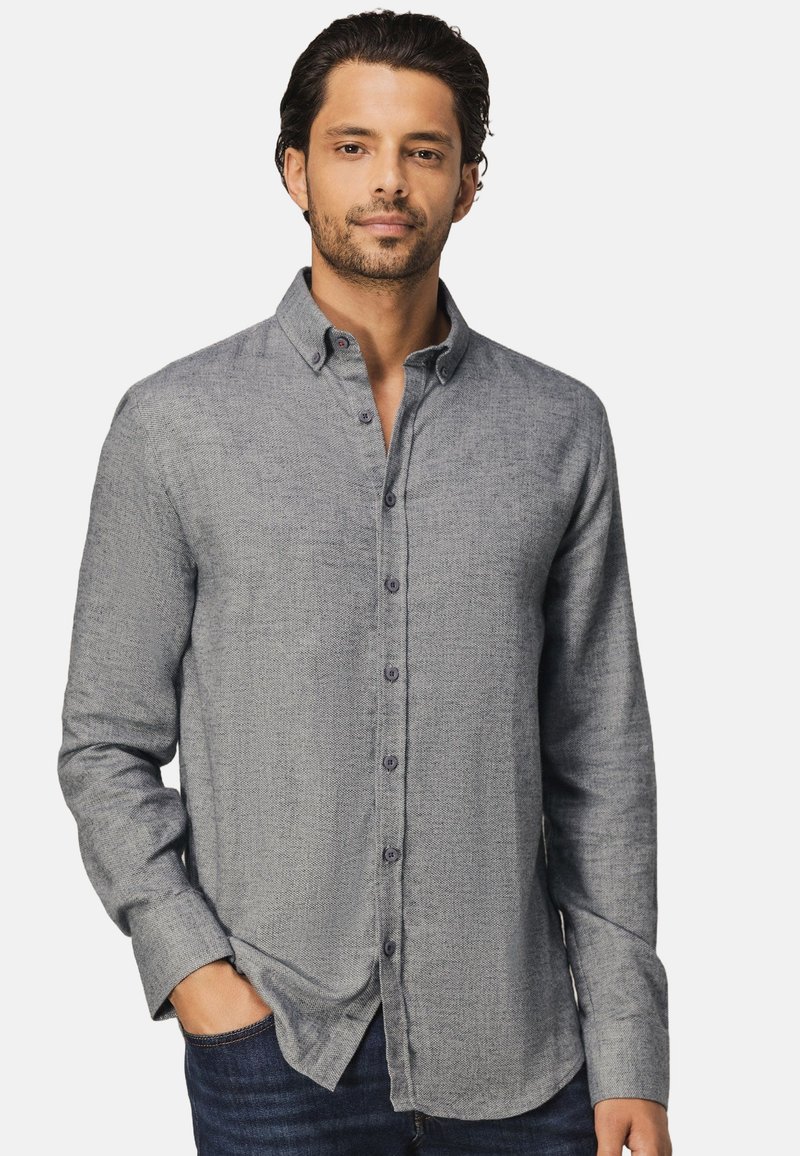 Lange mouw knoop-up shirt van lichtgrijze stof met een textuurpatroon, voorzien van een kraag en donkere knopen, gecombineerd met blauwe denim jeans.