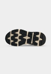 Semelle de chaussure avec motif de bande de roulement noir et beige présentant des formes géométriques et le nom de la marque Geox embossé au centre.