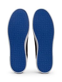 Ténis pretos com solas de borracha azuis, apresentando uma textura padrão e um acabamento branco nas bordas. O design inclui um estilo plano e minimalista.