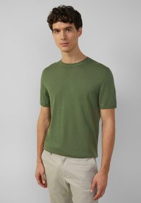 Groen T-shirt met korte mouwen en ronde hals, gemaakt van een gladde, lichte stof met een aansluitende pasvorm en een subtiele ribstructuur.