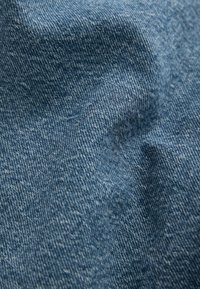 Denimfabric i ljusblått med en fin, strukturerad väv. Mjuk, flexibel, med små variationer i färg och subtil visuell djup.