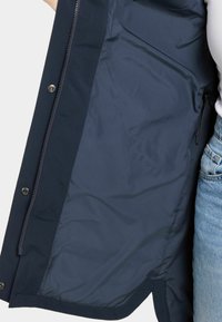 Navy blauwe jas interieur met een gladde textuur, voorzien van een rits en drukknoop sluting. Inclusief een zijzak voor opslag.