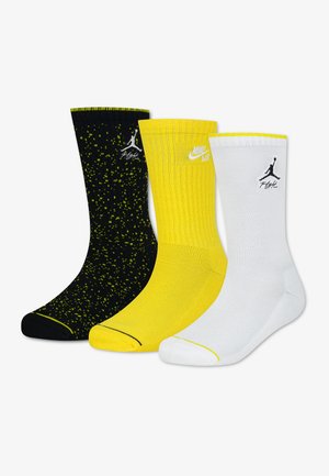 Tre par midt på læggen Nike-sokker i sort med gule pletter, helgule og helt hvide, hver med Jumpman- eller Nike Air-logoet.