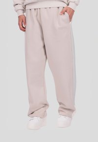 Világosszürke melegítőnadrág laza szabással, rugalmas derékpánttal, oldalzsebekkel és a lábon diszkréten dombornyomott logóval.