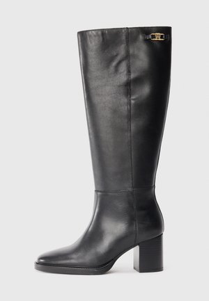 Black leather knee-high boot with a block heel, pointed toe, and gold hardware accent near the top. Smooth texture with minimal stitching.