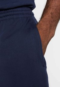 Joggers atléticos en navy confeccionados en una suave tela texturizada, con una cinturilla elástica y un bolsillo lateral, mostrando costuras detalladas y un ajuste perfecto.