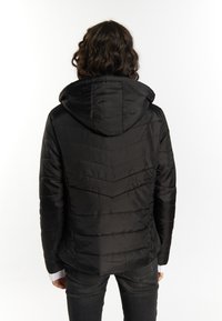 Jachetă puffer neagră cu glugă, prezentând un model cu quiltare în formă de zigzag, textură netedă și manșete elastice, stilizată cu o croială casuală.