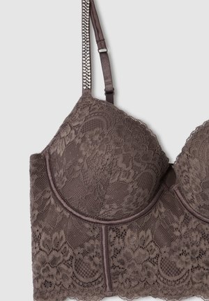 Reggiseno in pizzo marrone con motivi floreali, coppe imbottite, fascia sottile liscia e spalline regolabili con dettagli metallici decorativi.