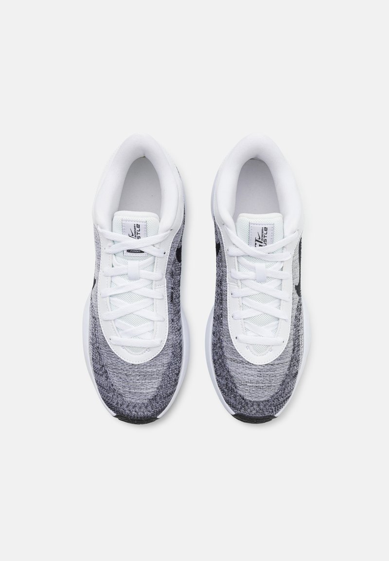 Baskets de sport avec une tige en tricot dans des nuances de gris et blanc, présentant une semelle blanche, un design à lacets et un logo noir subtil sur le côté.