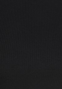 Tela negra acanalada con textura vertical; elástica y suave. Distribución del color uniforme sin patrones o acentos notorios.