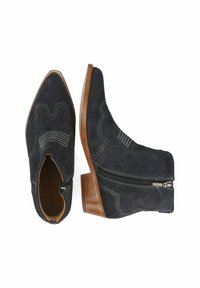 Botas de tobillo de ante azul oscuro con puntera afilada, costuras decorativas y cremalleras laterales. Los tacones de bloque de madera proporcionan un contraste con el material.