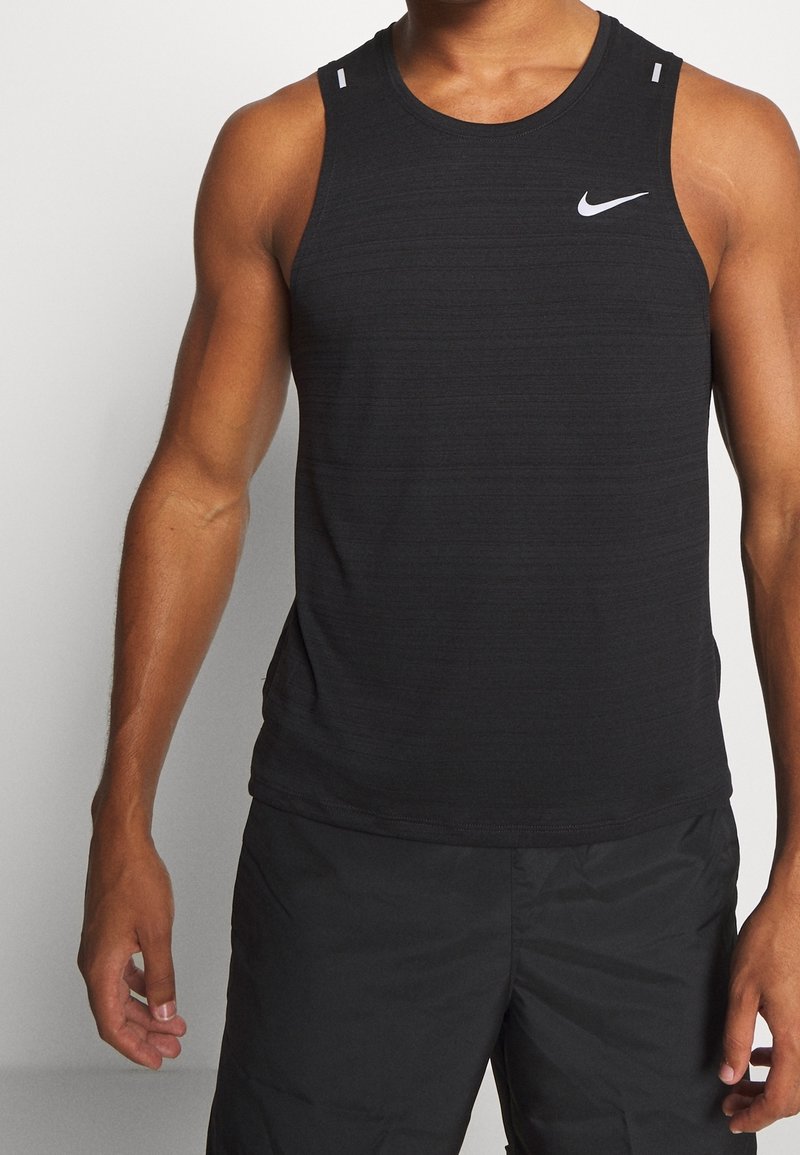 Czarny tank top Nike z teksturowanym wzorem, okrągłym dekoltem i dwoma małymi białymi akcentami na ramionach. Odpowiedni do użycia sportowego.
