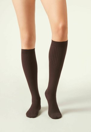 Bruine kniehoge sokken met verticale ribbelstructuur, een effen kleur en een strakke boord. De voet heeft de klassieke sokvorm.
