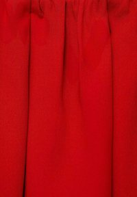 Tessuto rosso con una texture liscia, caratterizzato da pieghe e un design strutturato. Il materiale appare leggero e leggermente lucido.