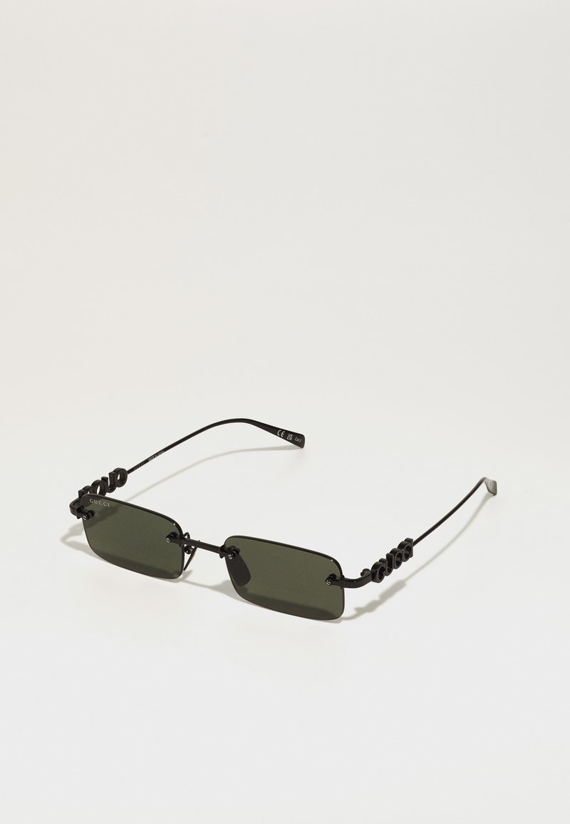 Gafas de sol de metal negro con lentes rectangulares de color verde oscuro, que presentan un diseño de marco retorcido único. Diseño minimalista con un branding sutil.