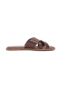 Sandale en cuir marron à glissière avec des brides croisées, semelle plate et design minimaliste. Les matériaux ont une texture lisse et une finition mate.