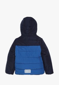 Kurtka puchowa z kapturem, charakteryzująca się granatowym górnym odcieniem i jasnoniebieską dolną częścią, z pikowanym wzorem oraz białym akcentem logo z tyłu.