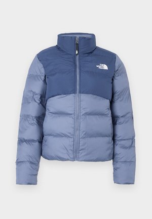 Puffer jakna u tamnoplavoj i svjetloplavoj boji sa patentnim zatvaračem sprijeda i logotipom The North Face na prsima, dizajnirana za hladno vrijeme.