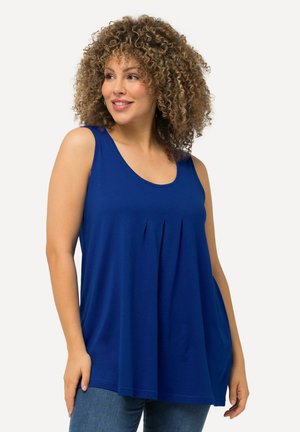 Königsblaue ärmellose Bluse aus weichem Stoff mit Rundhalsausschnitt und gefalteten Details auf der Vorderseite, kombiniert mit lässigen Jeans.