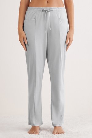 Lichtgrijze, rekbare loungebroek met een elastische tailleband, verstelbaar trekkoord en twee voorzakken. Gladde textuur en een ontspannen pasvorm.