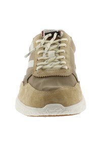 Scarpa sportiva beige con tomaia in pelle scamosciata e mesh, punta rotonda, suola bianca texturizzata e dettagli a strisce. I lacci sono beige con dettagli decorativi.