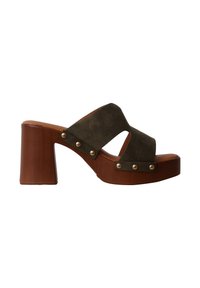 Sandale à plateforme en bois marron avec larges brides en daim vert foncé et détails de clous métalliques sur le côté.
