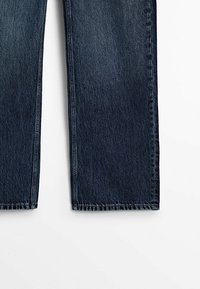 Tumman siniset farkut suoranlahkeisella leikkauksella. Ominaisuuksiin kuuluu teksturoitu kudos ja näkyvät ompeleet saumoissa. Taskuja ei ole näkyvissä.