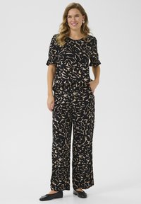 Ensemble coordonné noir et beige à motif comprenant un haut à manches courtes et un pantalon large, fabriqué dans un tissu doux avec une coupe décontractée.