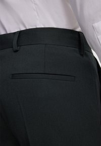 Zwarte formele broek met een gladde textuur, voorzien van een enkele achterzak, een platte voorkant en riemlussen. Het materiaal lijkt lichtgewicht en op maat gemaakt.
