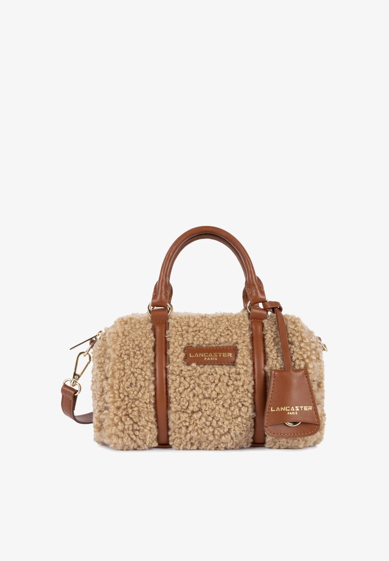 Sac à main en fausse fourrure beige avec des accents en cuir marron, poignées rondes, bandoulière amovible et plaque logo en relief doré.