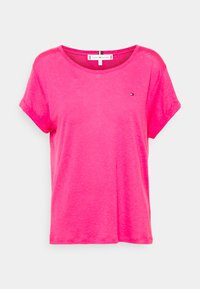 Camiseta de manga corta color rosa, confeccionada con una tela suave, con un cuello redondo y un pequeño logo en el lado izquierdo del pecho.