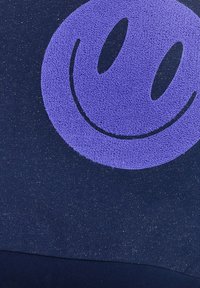 Navy fabric featuring a textured purple smiley face design, accentuated with subtle glimmering threads, creating a distinctive visual contrast.