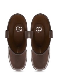 Botas de cuero marrón hasta el tobillo con textura suave, puntera redondeada y suela de goma blanca. Presentan dos asas para facilitar su uso. Logo en el interior.