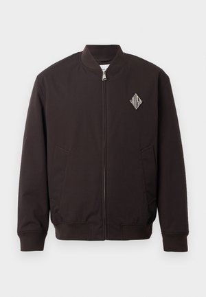 Chaqueta bomber negra con cuello redondo, cierre de cremallera, dos bolsillos laterales y un parche de logo en forma de diamante en el lado izquierdo del pecho.