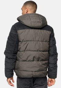 Puffer jacket in dark gray with a quilted design, corduroy accents on sleeves, and a hood. Features a smooth texture and snug fit.