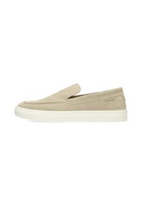 Zapatos beige sin cordones hechos de ante con una suela de goma blanca, que presentan costuras sutiles y un pequeño detalle del logotipo en el costado.