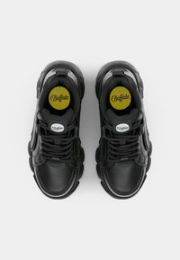 Ett par svarta Buffalo-sneakers med kraftiga sulor och svarta snören, sedd ovanifrån mot en vit bakgrund.