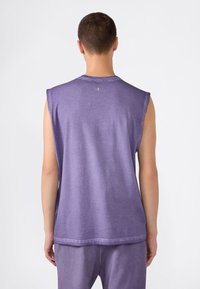 Fioletowa bezrękawnik z okrągłym dekoltem, miękka bawełniana tekstura oraz minimalistyczny design z logo na plecach.