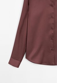 Long-sleeve shirt in deep burgundy, made of smooth fabric, featuring a button placket and a rounded hem with a folded cuff.