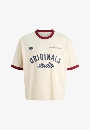 Lühikeste varrukatega kreemjas T-särk, millel on marooni tooni ribaga kaelus ja mansetid. Särk on varustatud prinditud tekstiga "ORIGINALS studio" ja ümmarguse logoga, millel on kirjas "1990".