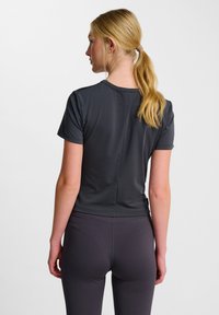 Grå atletisk t-shirt, kortärmad med en figurnära design. Slät, lättviktig tyg med rund hals och en subtil sömsdetalj bak.