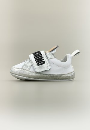 Sneaker per bambino piccolo bianco e argento con una larga fascia in velcro etichettata "MOSCHINO" e un anello per il trasporto sul tallone.