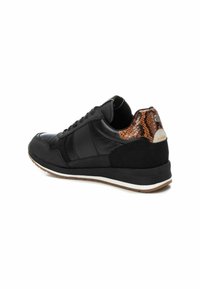 Zapatilla deportiva negra con parte superior de cuero y ante texturizado, que presenta un patrón de piel de serpiente en el talón y una suela de goma blanca.