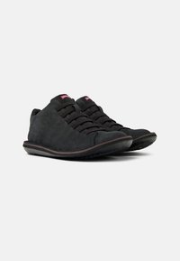 Scarpe in suede nero con punta arrotondata, design minimalista, allacciatura frontale e suola in gomma testurizzata. Presentano un branding sottile sulla linguetta.
