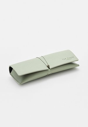 Custodia per occhiali Ted Baker verde chiaro con fascia elastica e chiusura con bottone, forma rettangolare, poggiata su una superficie bianca.