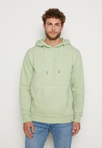 Lichtgroene hoodie met een kangoeroezak, verstelbare trekkoorden en geribde manchetten. Zacht materiaal met subtiel logo detail op de borst.