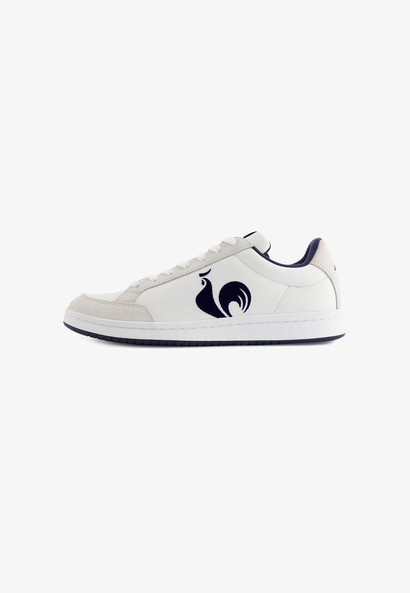 Baskets en cuir blanc avec des accents en suède gris, ornées d'un logo de coq bleu marine, de lacets ronds et d'une semelle en caoutchouc blanche.
