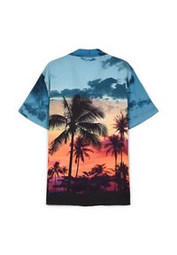La camicia a maniche corte presenta un design in gradiente blu e tramonto con grafiche di palme, realizzata in un tessuto leggero e liscio.
