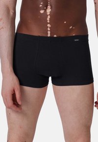 Boxer shorts neri in cotone con un design aderente e una texture liscia, caratterizzati da un piccolo etichetta sulla vita.